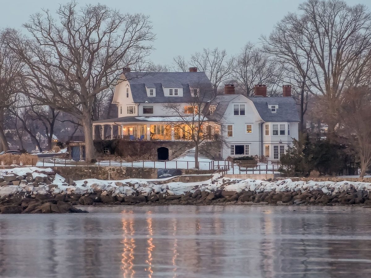 A coastal home lit from within at dusk